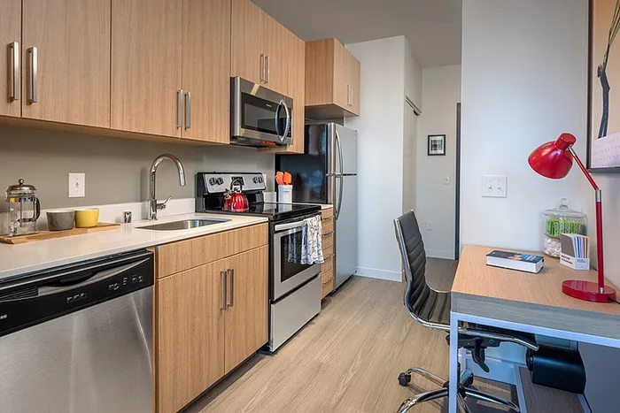 Model apartment kitchen with light brown cabinets and stainless steel appliances