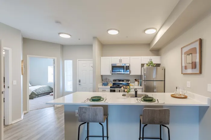 Model apartment kitchen with stainless steel appliances, white cabinets, and quartz countertop