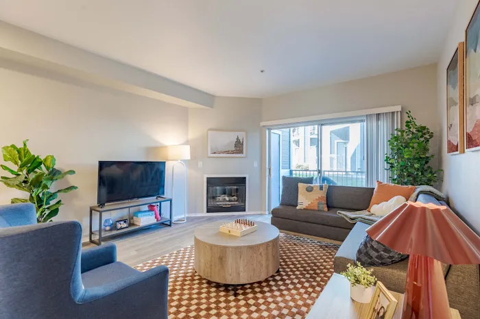 Model apartment living room with hardwood flooring, white walls, and glass sliding doors leading to the balcony