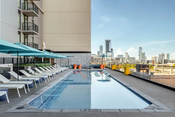 Pool surrounded by lounge chairs and views of the city at Union on San Antonio, new apartments in Austin, TX.
