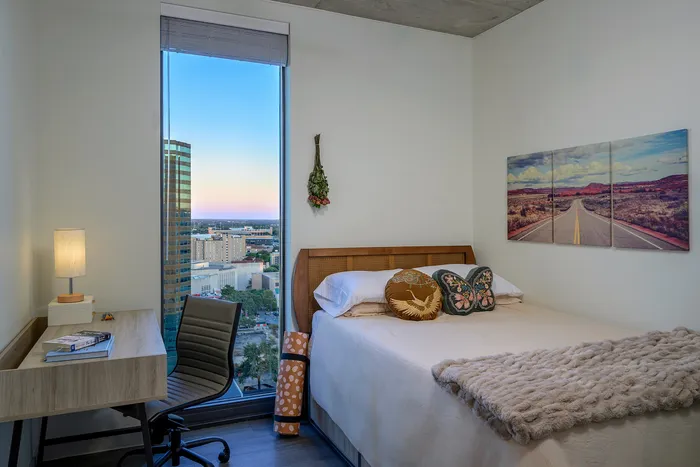 Furnished bedroom with a floor-to-ceiling window at Union on San Antonio new apartments in Austin, TX.
