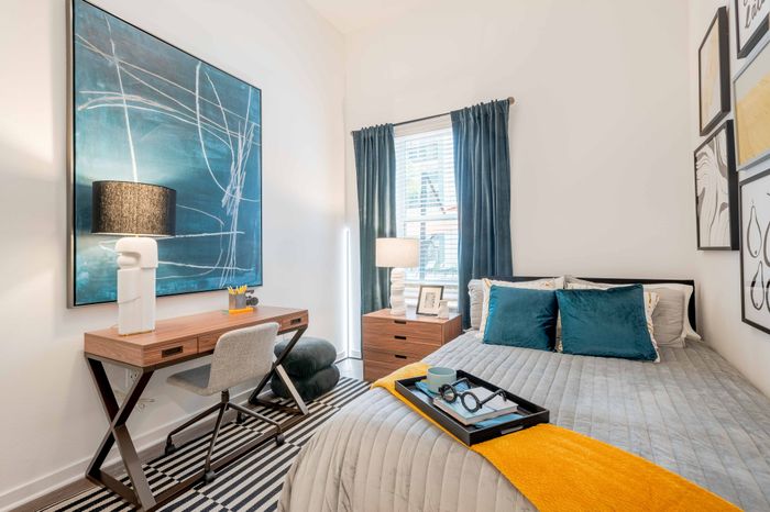 Model apartment bedroom with a full size bed, desk, chair, and dresser at The Accolade Collegiate Village East apartments for rent in Orlando, FL.