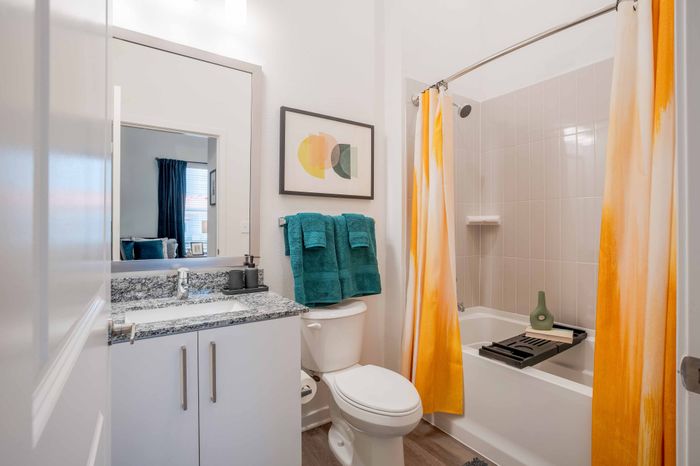 Model apartment bathroom with granite countertops and white cabinets