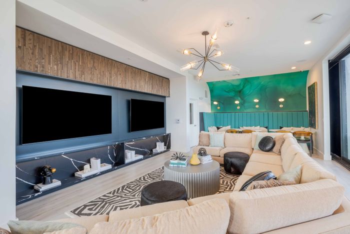 Clubhouse media room with sofas and two flat screen TVs at The Accolade Collegiate Village East apartments in Orlando, FL.