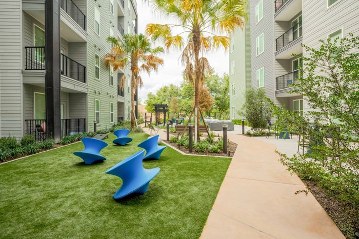 Community clubhouse media room with couch seating and two flat screen TVs at The Accolade Collegiate Village East modern apartments in Orlando.