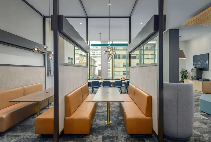 Common lounge at our apartments in Seattle, featuring carpeted floors, cushioned chairs, and large windows.