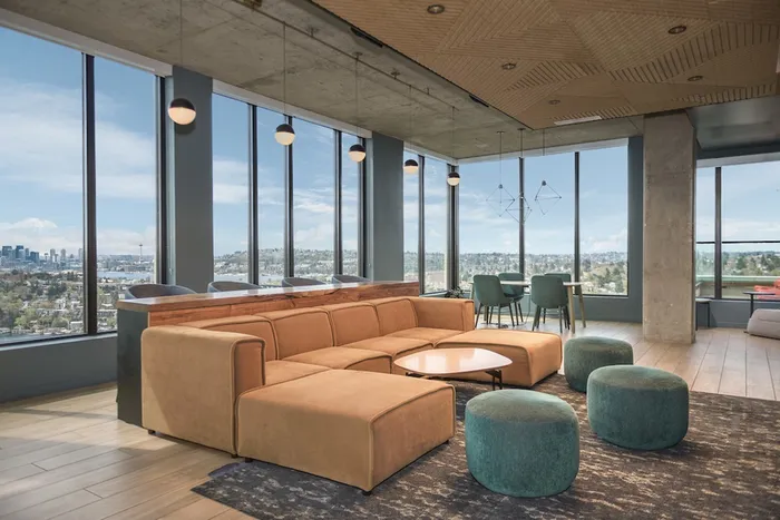 Common lounge with comfy couch with large windows looking out at the Seattle skyline.