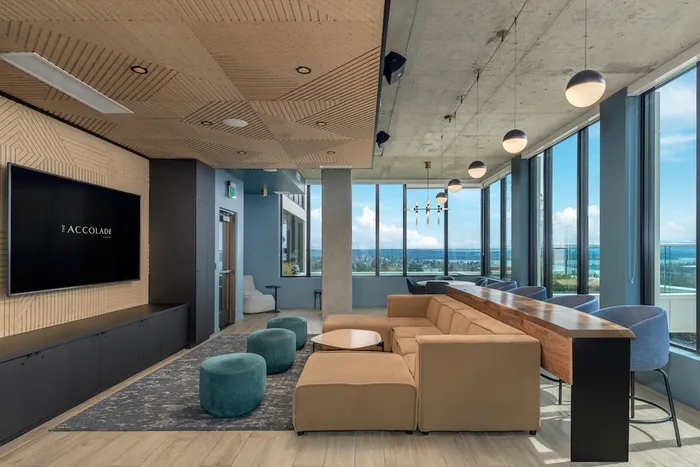 Media lounge with large tv, comfy couch, and large windows looking out at the Seattle skyline.