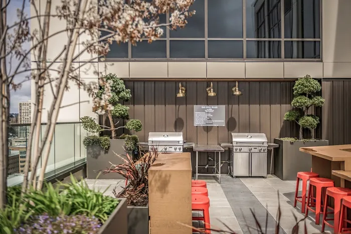 Rooftop lounge with two grills and seating.