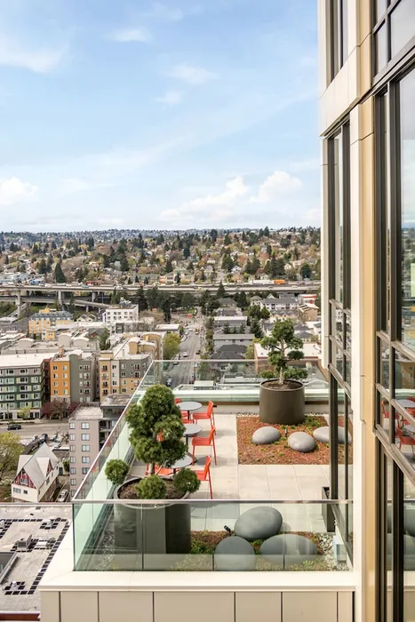 Rooftop balcony with lounge chairs and tables overseeing the Seattle skyline.