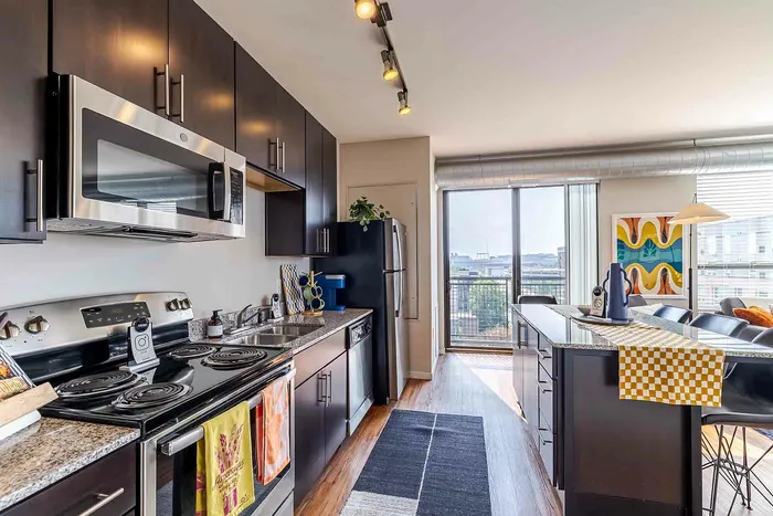 Model unit kitchen with dark brown cabinets, stainless steel appliances, and wood style flooring