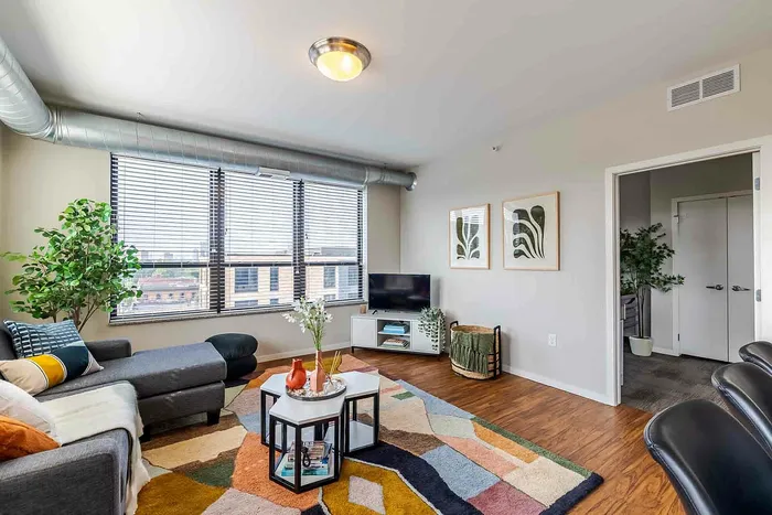 Model unit living room with light gray walls, wood style flooring, and modern furnishings
