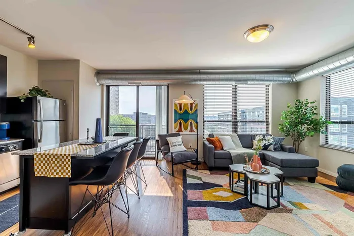 Model unit open concept living room and kitchen with floor to ceiling windows