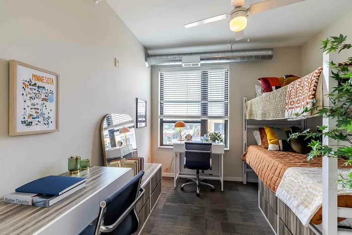 Model unit bedroom with bunk beds, drawers, desks, chairs, and a large window