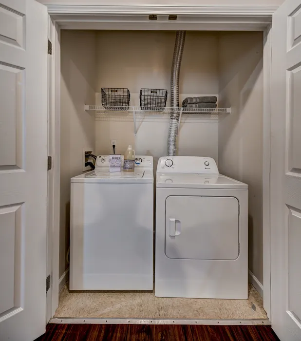 Practical in-unit laundry with modern washer and dryer, elegant shelving, and ample storage space.