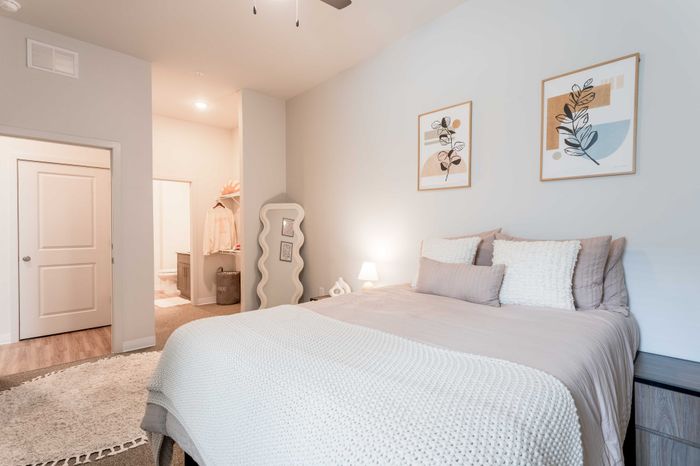 Cozy bedroom with modern decor, featuring a plush bed, stylish artwork, and elegant lighting, perfect for relaxation.