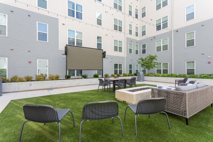 Chic modern apartment courtyard with lush green lawn, stylish seating, and a sleek fire pit perfect for outdoor gatherings.