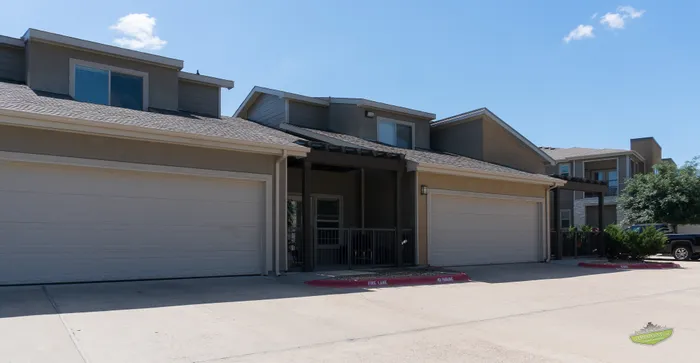 Charming townhouse with two-car garage, set under a clear blue sky, offering modern design and ample driveway space.
