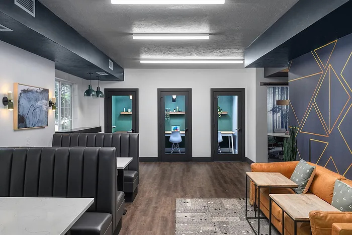Modern co-working space with elegant booths, vibrant wall art, and cozy seating area, featuring individual work rooms with stylish decor.