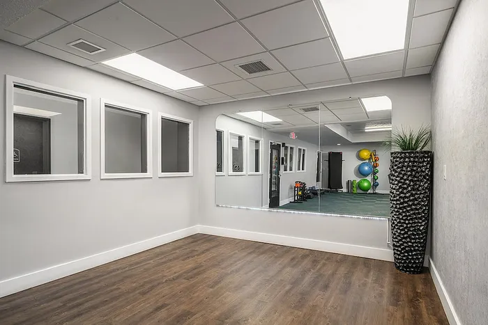 Modern exercise room with sleek wood flooring, large mirrors, and vibrant fitness equipment for a dynamic workout atmosphere.