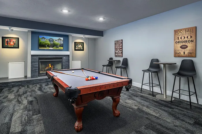 Chic recreational room featuring a stylish pool table, cozy fireplace, and modern bar seating.