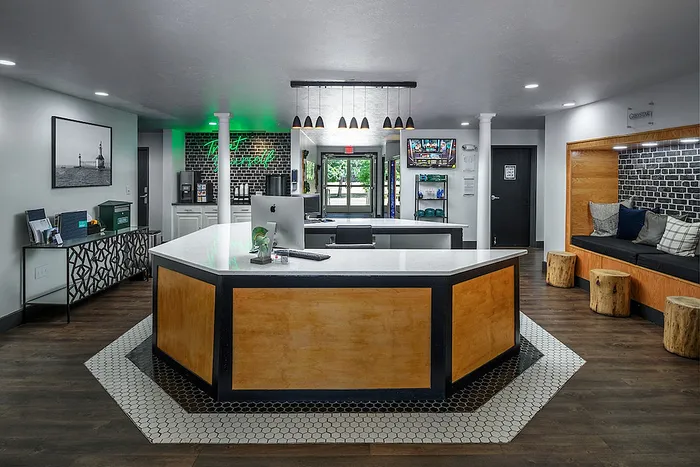 Modern apartment lobby with sleek hexagonal reception desk, cozy seating area, and stylish decor.