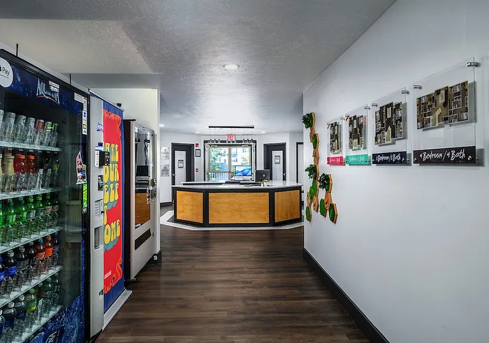 Modern apartment lobby with a sleek reception desk, vibrant vending machines, and floor plans displayed on the wall, creating an inviting atmosphere.