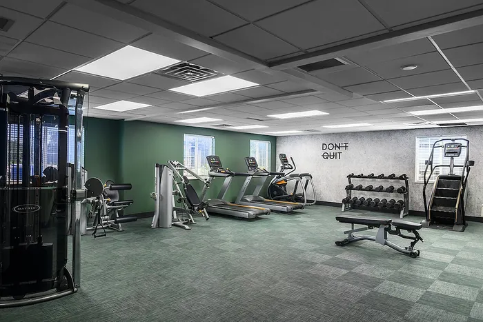 Modern fitness center with state-of-the-art gym equipment, inspiring 'Don't Quit' mural, and ample natural light.
