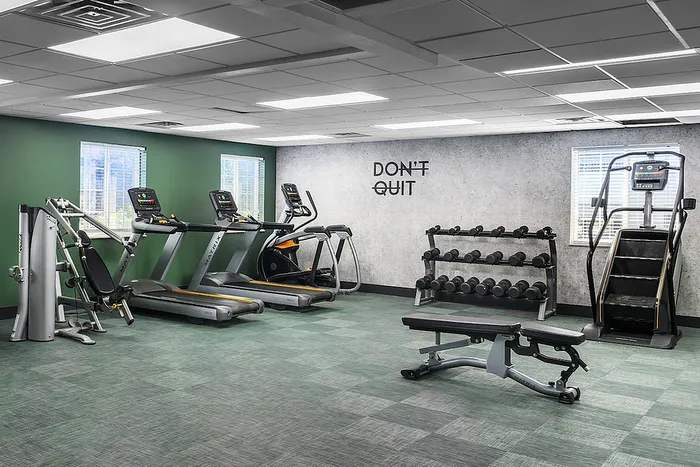 Inviting fitness center with modern exercise equipment, including treadmills, weights, and a motivational 'Don't Quit' sign.