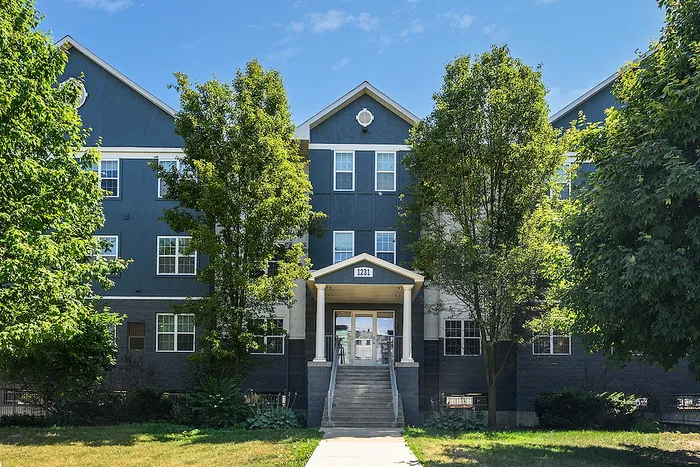 Charming residential building with modern design, surrounded by lush greenery and bright blue sky.
