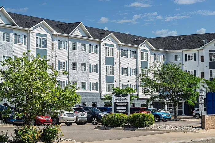 Modern apartment complex with elegant architecture, featuring lush landscaping and ample parking space.