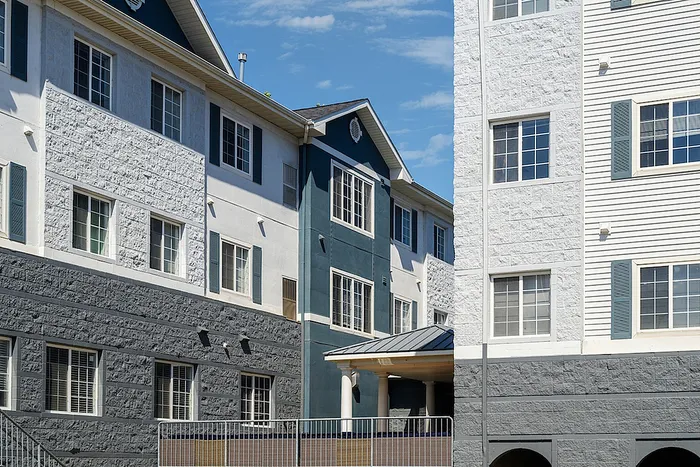 Charming residential building with modern architecture, featuring crisp white and gray exteriors and large windows, offering a welcoming and stylish living space.