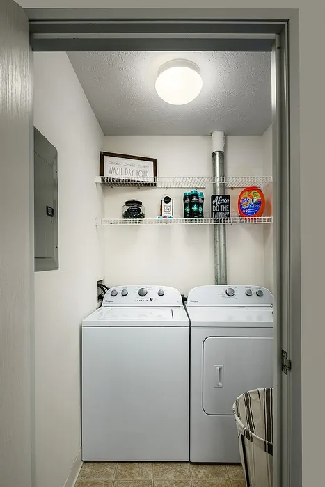 Bright and efficient laundry room featuring modern washer and dryer, with ample shelving and essential cleaning supplies.