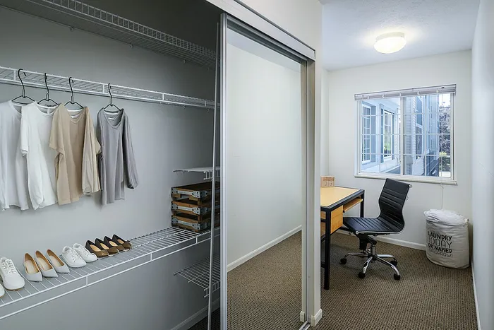 Bright and inviting room featuring a sleek workspace and a well-organized closet, perfect for modern living.