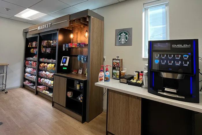 Modern mini market and coffee station with a variety of snacks and a sleek coffee machine.