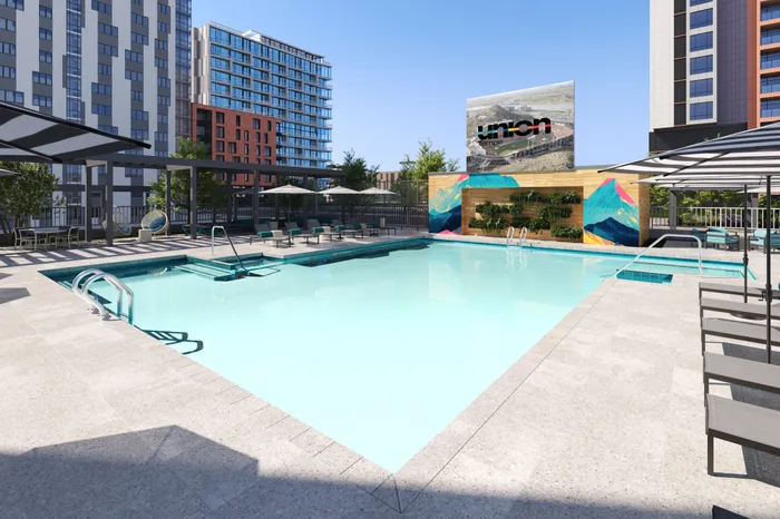 Luxury apartment in Tempe swimming pool with modern lounge chairs, vibrant mural, and sleek cityscape views with a Union Tempe sign overlooking area.