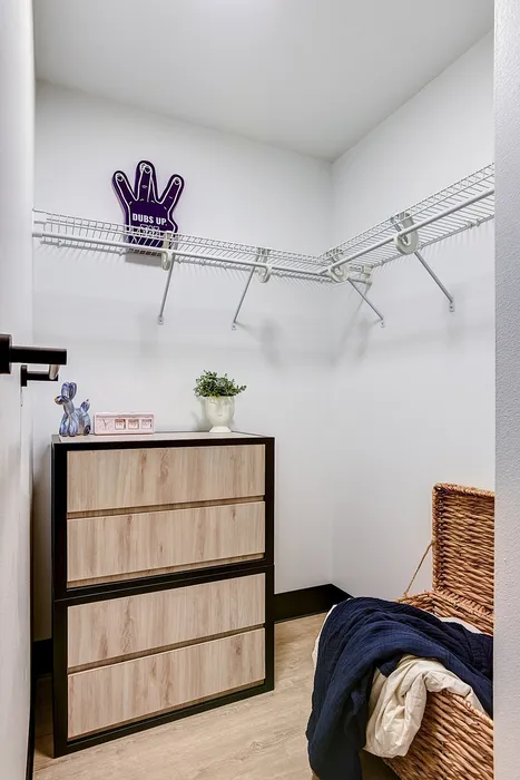 Spacious walk-in closet with modern shelving, sleek wooden dresser, and charming decorative touches.