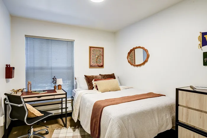 Inviting bedroom with modern decor, featuring a cozy bed, stylish desk, and elegant wall art, perfect for relaxation.