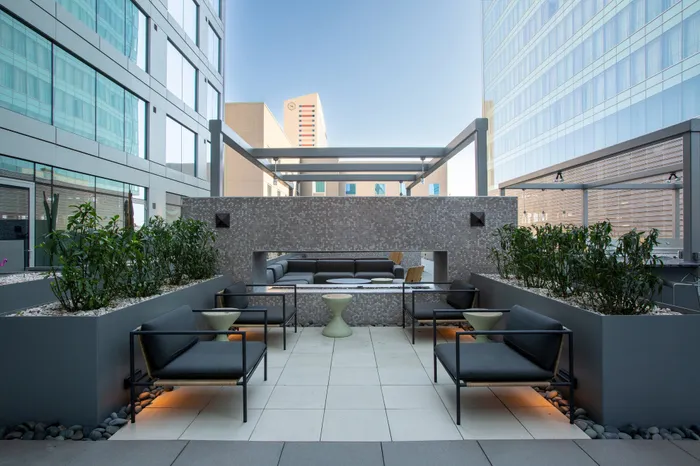 Modern outdoor terrace featuring sleek seating, elegant planters, and a stylish pergola amidst city skyscrapers.