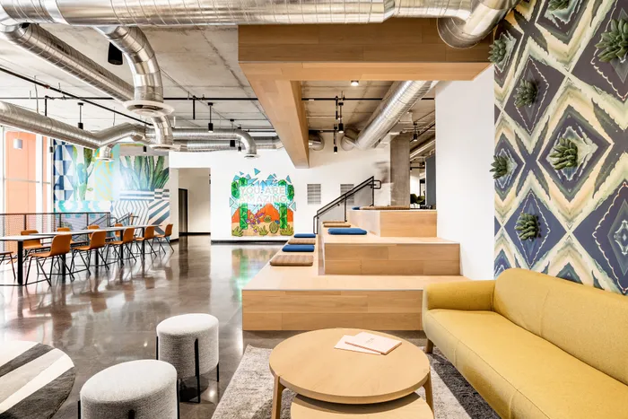 Open-concept lounge with vibrant murals, stylish wood seating at Sora apartments in downtown Phoenix, AZ.