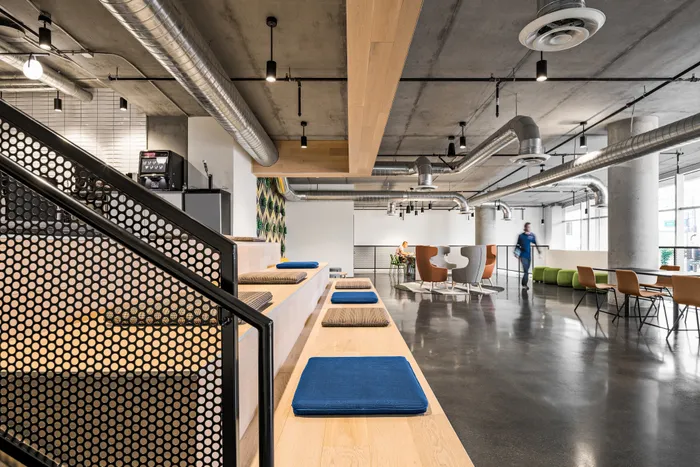 Modern industrial-style office space with sleek seating, stylish decor, and exposed ductwork for an open and creative environment.