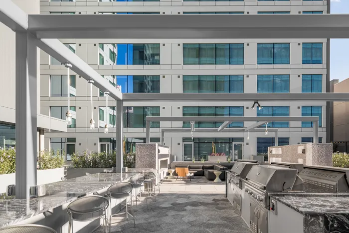 Luxurious outdoor patio featuring sleek marble countertops, plush seating, and modern barbecue grills in an urban high-rise setting.