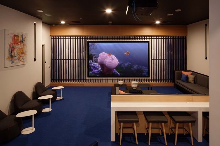 Luxurious home theater with plush seating, vibrant wall art, and a large screen with colorful animation, perfect for entertainment.