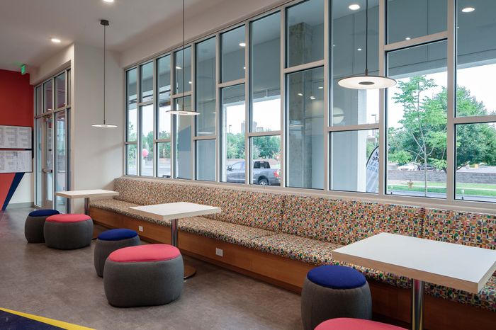 Modern apartment lounge area with colorful seating, chic pendant lighting, and large windows inviting natural light.