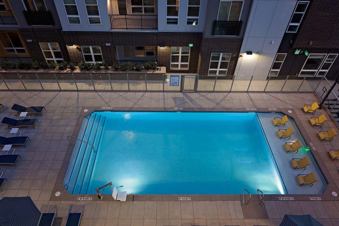 Chic outdoor swimming pool area with lounge chairs and modern apartment backdrop, perfect for relaxation and leisure.