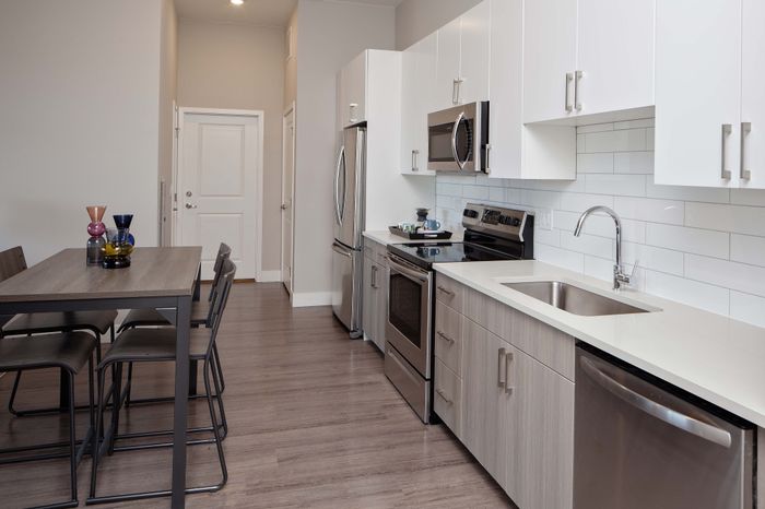 Modern kitchen with sleek stainless steel appliances, spacious dining area, and elegant cabinetry in a contemporary apartment setting.
