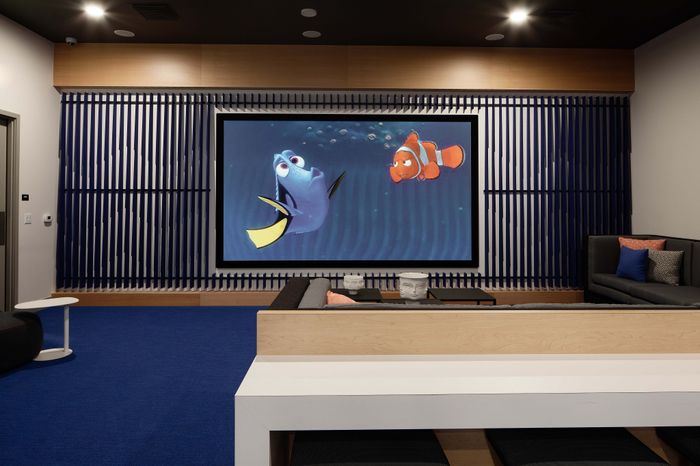 Modern entertainment room featuring a large screen displaying colorful animation, cozy seating, and stylish decor in a vibrant setting.
