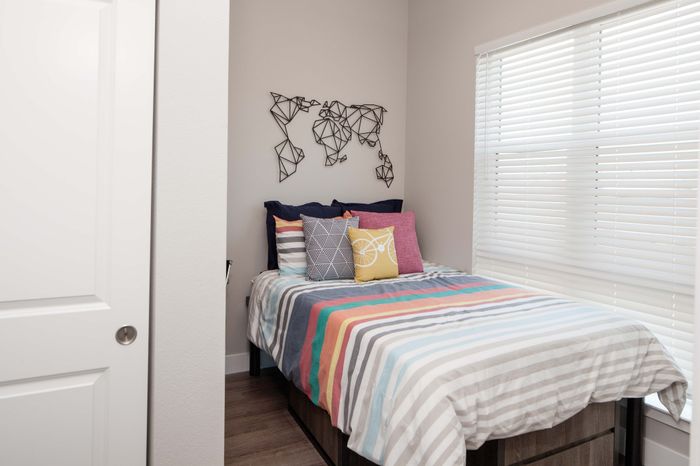 Cozy bedroom with a colorful striped bedspread, vibrant throw pillows, and a modern geometric wall art accent.