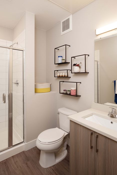 Modern bathroom with sleek tile shower, elegant shelving, and stylish wood vanity.