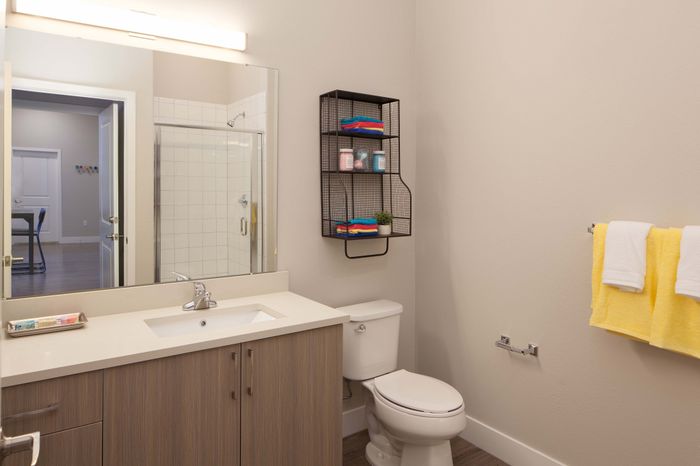Modern bathroom featuring sleek cabinetry, a large mirror, and stylish shower area with vibrant towels and decor for a fresh look.